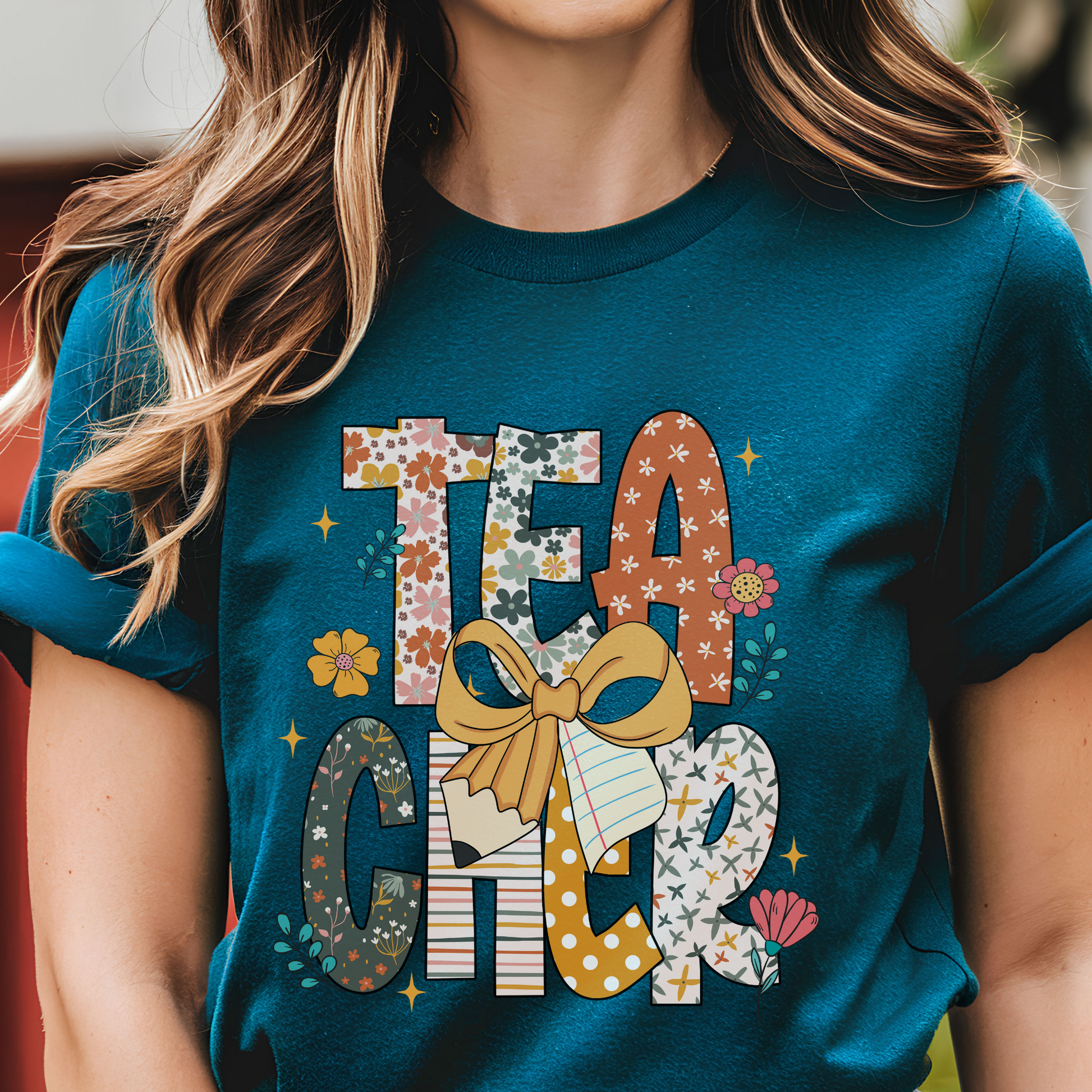 Person wearing a teal t-shirt with 'TEACHER' printed in decorative letters.