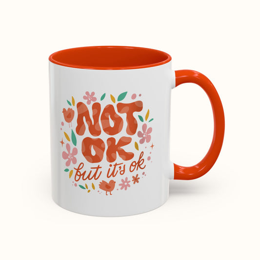 Mug with 'Not ok but it's ok' text and floral design on a white background