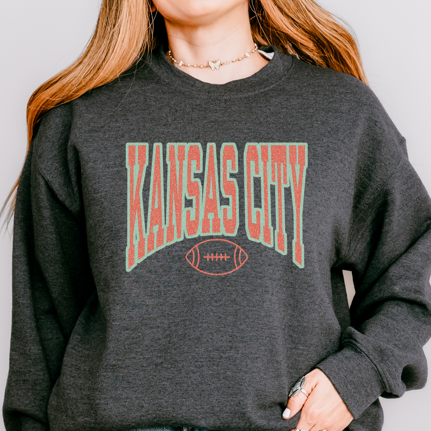 Person wearing a dark gray sweatshirt with 'Kansas City' printed on it.