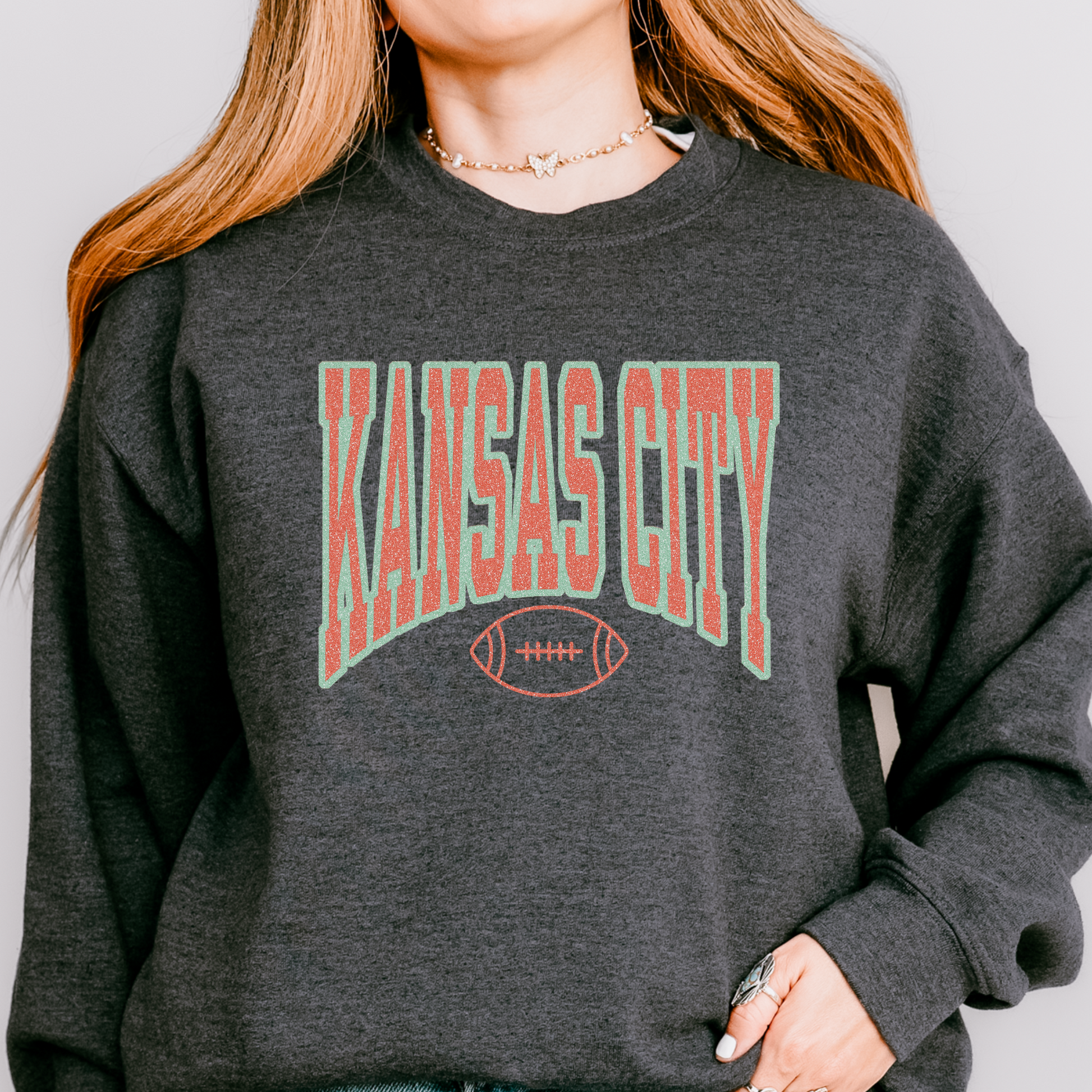 Person wearing a dark gray sweatshirt with 'Kansas City' printed on it.