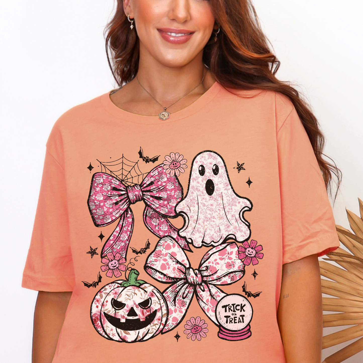 Person wearing a peach t-shirt with Halloween-themed graphics including a ghost, pumpkin, and bows.
