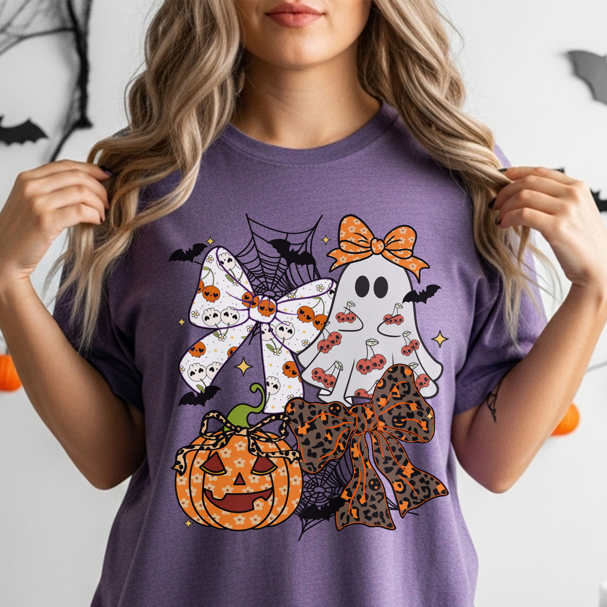 Person wearing a purple t-shirt with Halloween-themed graphics including bows, ghosts, and pumpkins.