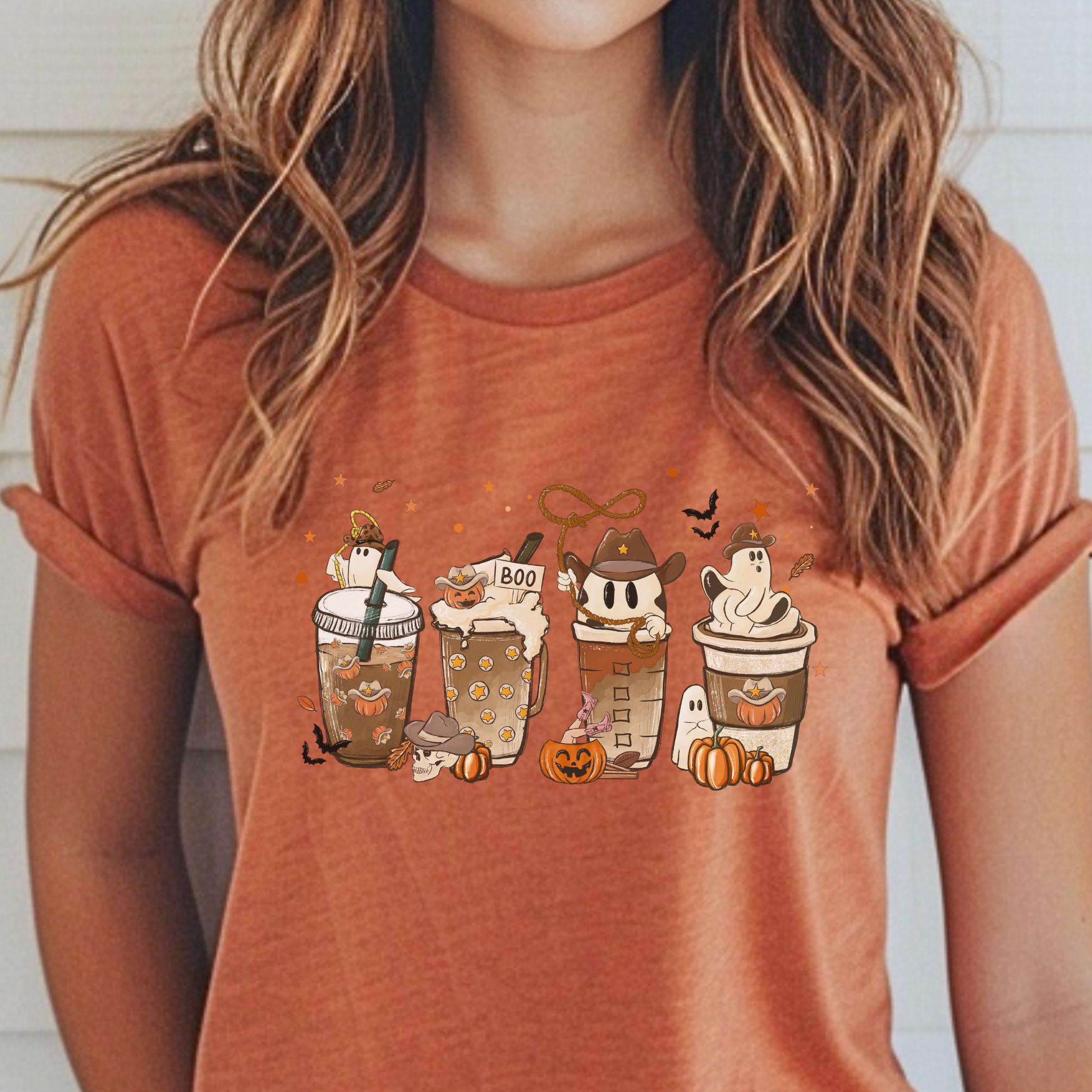 Person wearing a terracotta-colored t-shirt with Halloween-themed coffee cup graphics.